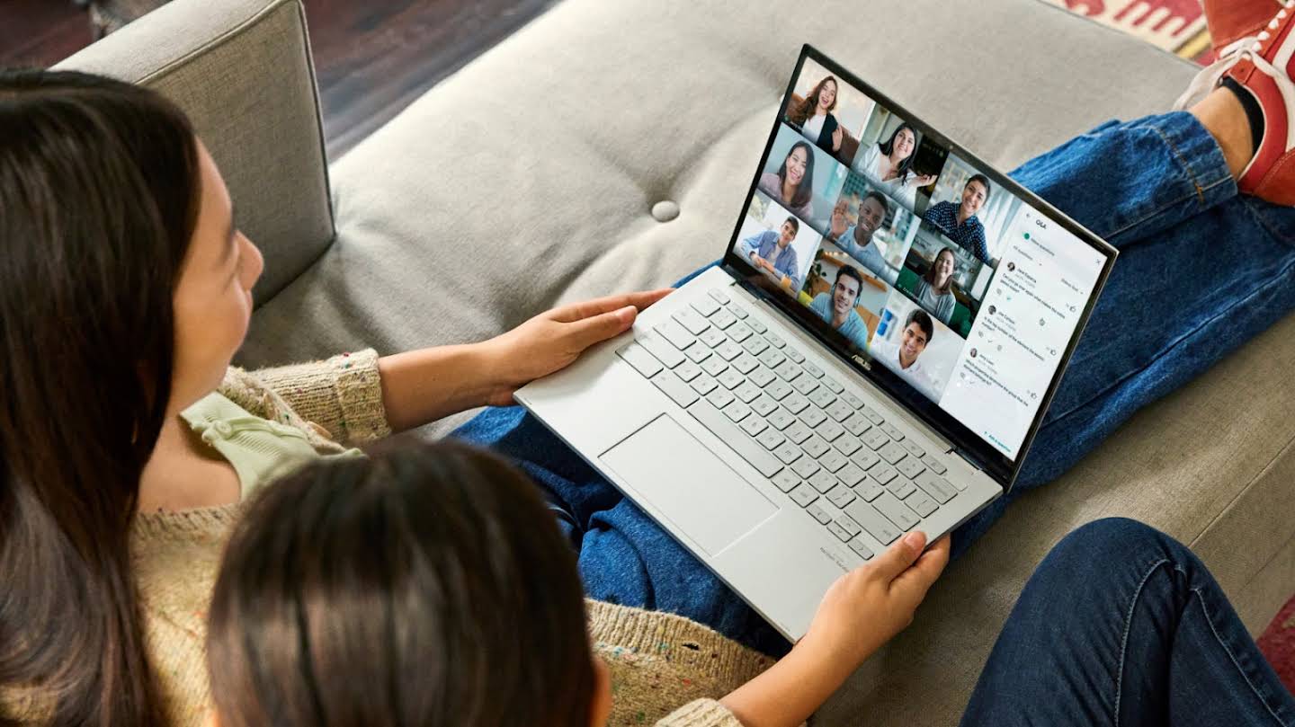 Em um sofá, duas pessoas participam de uma chamada do Google Meet.