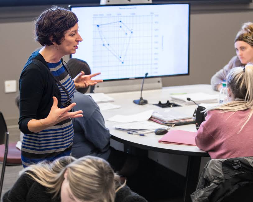 A teacher is lecturing in the middle of a classroom.